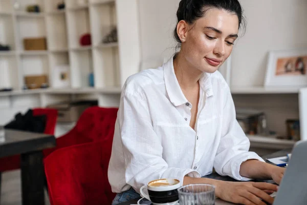 Kafede Oturup Dizüstü Bilgisayar Kullanan Mutlu Genç Bir Kadının Görüntüsü — Stok fotoğraf