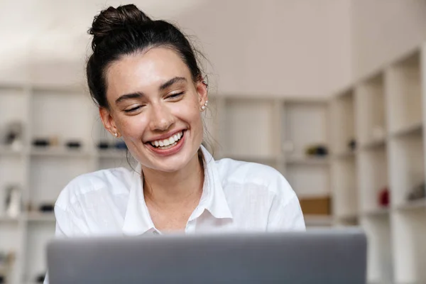 一个年轻漂亮 快乐的女人坐在室内的咖啡厅里 用笔记本电脑的照片 — 图库照片