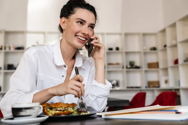 Mujer Joven Sonriente Desayunando Café Interior Usando Teléfono Móvil — Foto de Stock