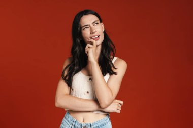 Düşünceli, düşünceli bir kadının görüntüsü. Kırmızı arka planda izole edilmiş bir şekilde.