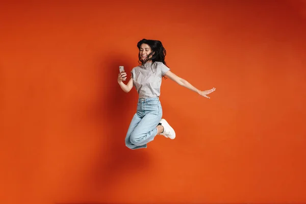 Imagen Una Joven Mujer Alegre Saltando Usando Teléfono Celular Aislado —  Fotos de Stock