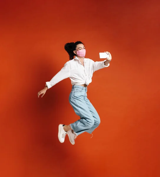 Kırmızı Arka Planda Izole Edilmiş Cep Telefonundan Atlayan Selfie Çeken — Stok fotoğraf
