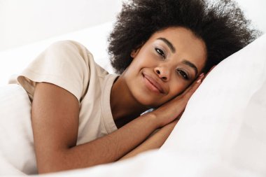 Gülümseyen güzel Afrikalı bir kadın yatakta uyuyor.
