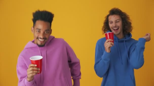 Δύο Χορευτές Πίνουν Από Πλαστικά Ποτήρια Που Απομονώνονται Πορτοκαλί Φόντο — Αρχείο Βίντεο