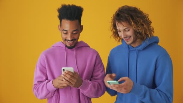 Les Gars Positifs Utilisent Leurs Smartphones Isolés Sur Fond Orange — Video