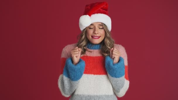 年轻的 充满希望的快乐女人 戴着圣诞礼帽 手指交叉在红墙的背景上 — 图库视频影像