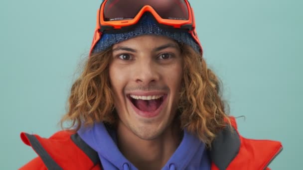 Snowboarder Sorridente Está Olhando Para Câmera Isolado Sobre Fundo Azul — Vídeo de Stock