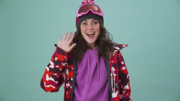 Happy Woman Snowboarder Doing Hello Gesture Standing Isolated Blue Background — Stock Video