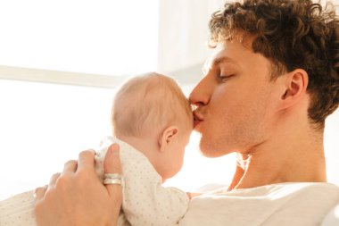 Mutlu genç baba, evde yatıp kucaklaşırken küçük oğluyla oynuyor.