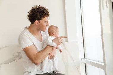 Mutlu genç baba, evde yatıp kucaklaşırken küçük oğluyla oynuyor.