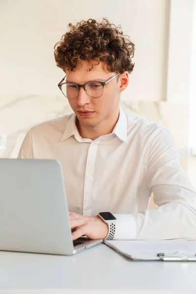 坐在桌旁 身穿白衬衫 在笔记本电脑上工作 自信迷人的年轻商人 — 图库照片