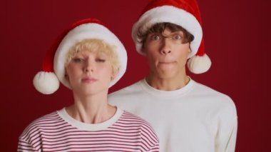 Noel Baba şapkalı kardeşiyle mutlu, genç, tatlı bir kız. Kırmızı duvar arka planında izole edildiğin konusunda seninle aynı fikirde.