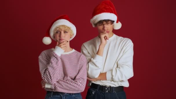 Joven Pensando Chica Positiva Con Hermano Navidad Sombrero Santa Aislado — Vídeos de Stock
