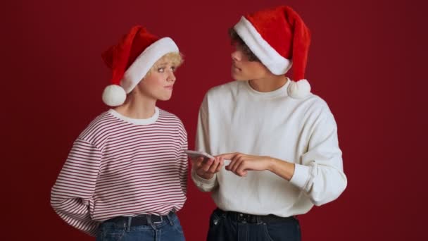 Joven Chica Concentrada Utilizando Teléfono Móvil Con Hermano Navidad Sombrero — Vídeo de stock