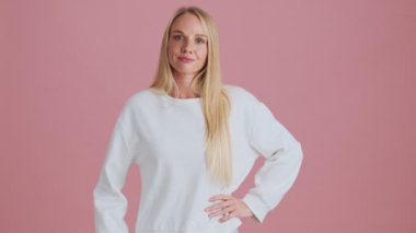 Ciddi bir sarışın kadın parmağını sallıyor. Stüdyoda pembe arka planda duran negatif bir hareket sergiliyor.