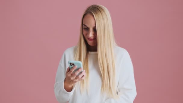 Överraskad Blond Kvinna Tittar Sin Smartphone Och Gör Vinnaren Gest — Stockvideo
