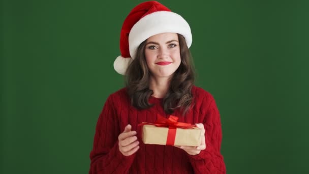 悲しい女の子でクリスマスサンタ帽子保持存在しながら親指アップと表示しないようにしようとしている間彼女は動揺しています絶縁されています緑の壁の背景 — ストック動画
