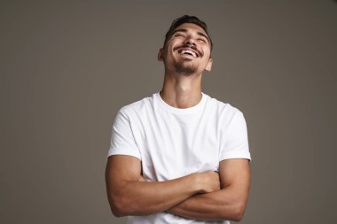 Gri arka planda kolları çaprazlanmış, kamerada poz veren gülmeyen adamın görüntüsü.