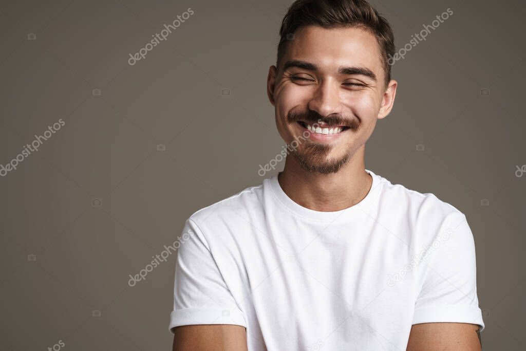 Image of joyful unshaven guy laughing while posing on camera isolated over grey background