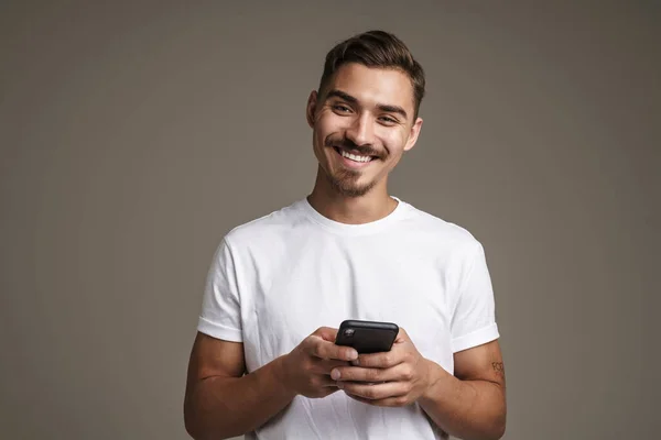 Image Joyful Unshaven Guy Smiling Using Cellphone Isolated Grey Background — Stock Photo, Image