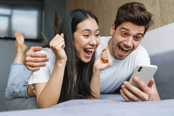 Szczęśliwa Para Korzystająca Treści Multimedialnych Smartfonie Podczas Relaksu Kanapie Domu — Zdjęcie stockowe