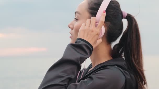 Junge Hübsche Sportlerin Hört Draußen Strand Musik Mit Kopfhörern — Stockvideo