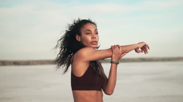 Eine Attraktive Afrikanisch Amerikanische Frau Sportbekleidung Streckt Strand Stehend Ihre — Stockvideo