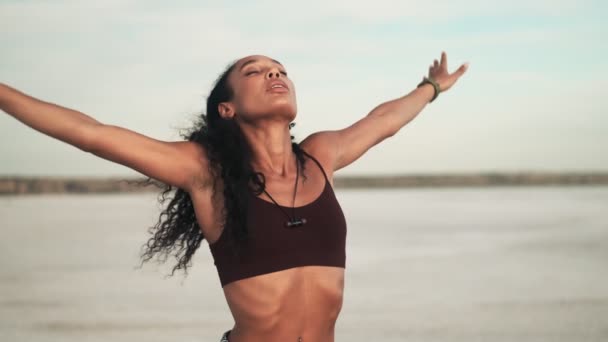一位漂亮的身穿运动服的非洲裔美国女人站在海滩外进行体育锻炼 — 图库视频影像