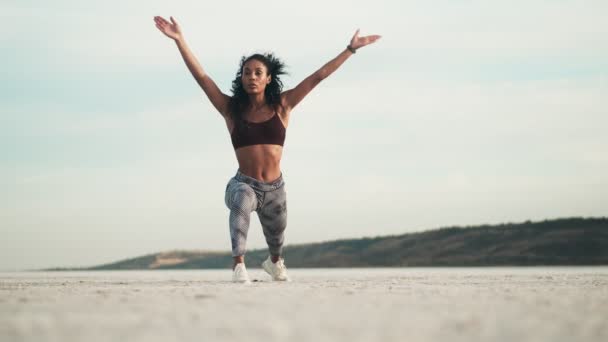 Skoncentrowana Afroamerykanka Odzieży Sportowej Rozprostowuje Nogi Stojąc Plaży — Wideo stockowe