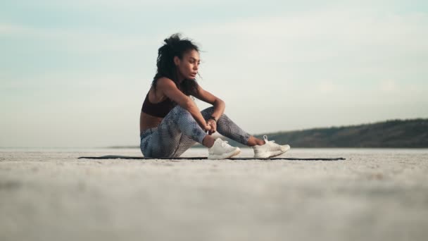 Eine Ruhige Afroamerikanerin Sportbekleidung Sitzt Draußen Strand Auf Der Yogamatte — Stockvideo