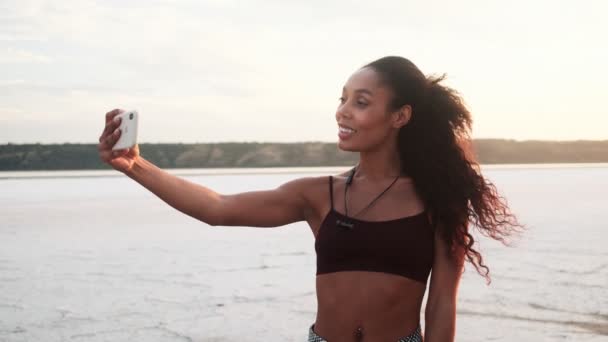 Vacker Ung Afrikansk Amerikansk Kvinna Sportkläder Tar Selfie Foto Stranden — Stockvideo
