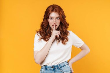 Kızıl heyecanlı kızın sarı arka planda izole edilmiş sessizlik hareketi görüntüsü