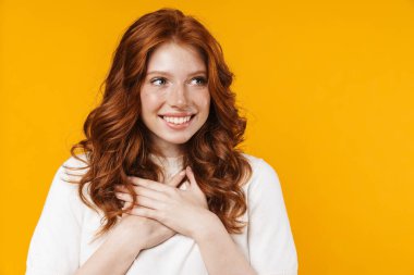 Kızıl, heyecanlı bir kız görüntüsü. Elleri göğsünde, sarı arka planda mahsur kalmış bir şekilde şaşkınlığını ifade ediyor.