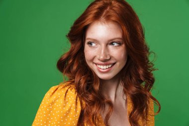Kızıl, neşeli kızın yeşil arka planda izole edilmiş bir şekilde gülüşü ve bakışları.