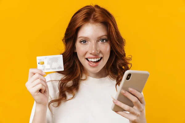 Imagem Menina Feliz Gengibre Segurando Cartão Crédito Usando Celular Isolado — Fotografia de Stock