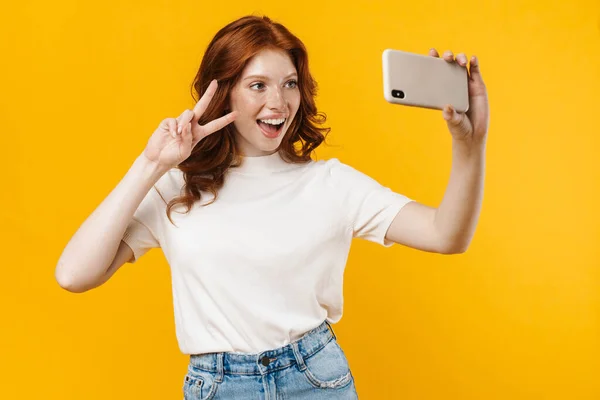 소녀가 노란색 배경으로 휴대폰으로 셀카를 표시를 — 스톡 사진