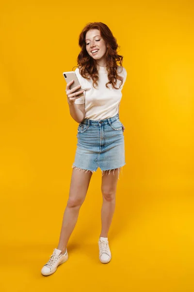 Image Ginger Happy Girl Smiling Using Mobile Phone Isolated Yellow — Stock Photo, Image