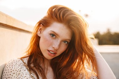 Şehir caddesinde poz veren ve kameraya bakan mutlu kızıl kız görüntüsü