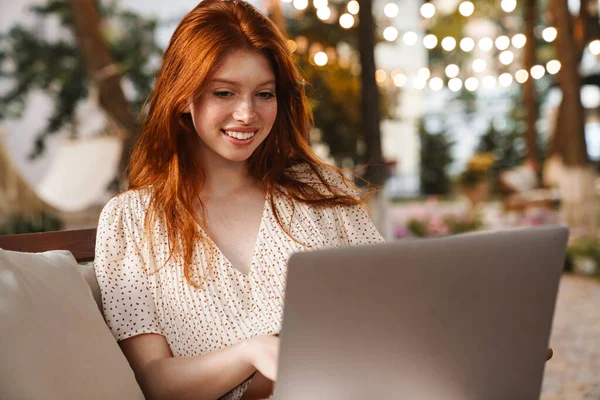 Kızıl Saçlı Mutlu Bir Kızın Yazın Kafede Otururken Bilgisayarla Gülümsemesi — Stok fotoğraf