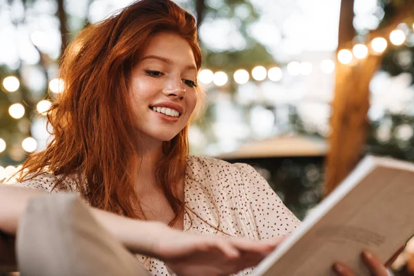 Afbeelding Van Vrolijke Gember Meisje Glimlachen Lezen Boek Tijdens Het — Stockfoto