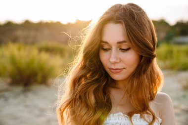 Beyaz tenli, çekici, esmer bir kadın, dışarı çıkarken aşağıya bakıyor.