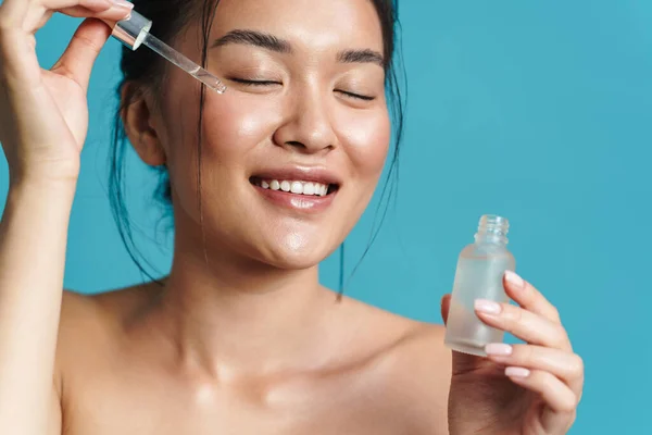 Imagem Menina Asiática Sem Camisa Feliz Aplicando Soro Facial Isolado — Fotografia de Stock