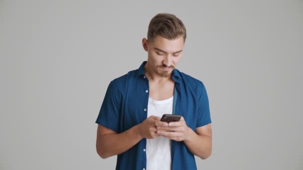 Homme Concentré Utilise Son Smartphone Isolé Sur Fond Gris Studio — Video