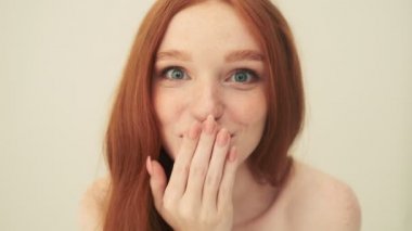 Mutlu bir kadının yakın çekimi stüdyodaki bej arka planda izole bir şekilde duran kameraya bakıyor.