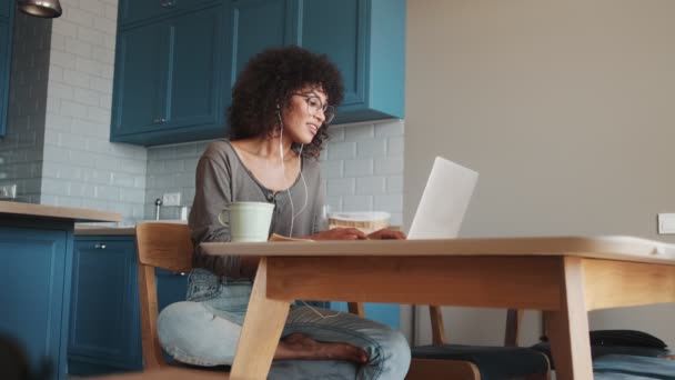 Mujer Africana Concentrada Sentada Casa Usando Ordenador Portátil Mientras Escucha — Vídeo de stock