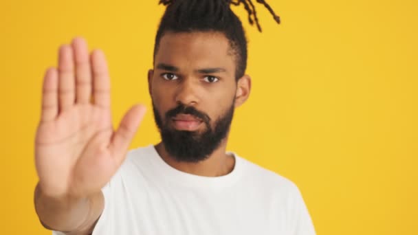若い深刻なアフリカ人男性ショーストップ孤立上黄色の背景 — ストック動画