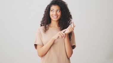 Çekici bir Afrikalı Amerikalı kadın bej arka planda tek başına duran parmaklarına güveniyor.