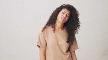 Sıkılmış bir Afrikalı Amerikalı kadın esniyor bej arka planda tek başına duruyor.