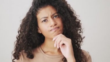 Ciddi bir Afrikalı Amerikalı kadının yakın plan görüntüsü, bej arka planda tek başına duran negatif bir şekilde başını sallıyor.