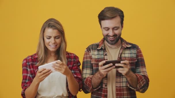 Szczęśliwa Para Mężczyzna Kobieta Grają Gry Pomocą Smartfonów Stojących Żółtym — Wideo stockowe